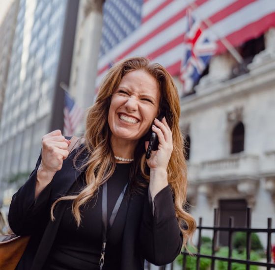 Excited Woman Using Mobile Phone on a Street and US Flag in Background