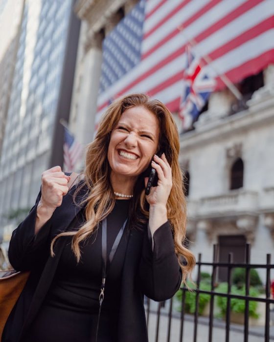 Excited Woman Using Mobile Phone on a Street and US Flag in Background