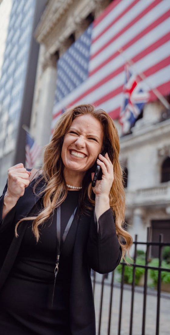 Excited Woman Using Mobile Phone on a Street and US Flag in Background